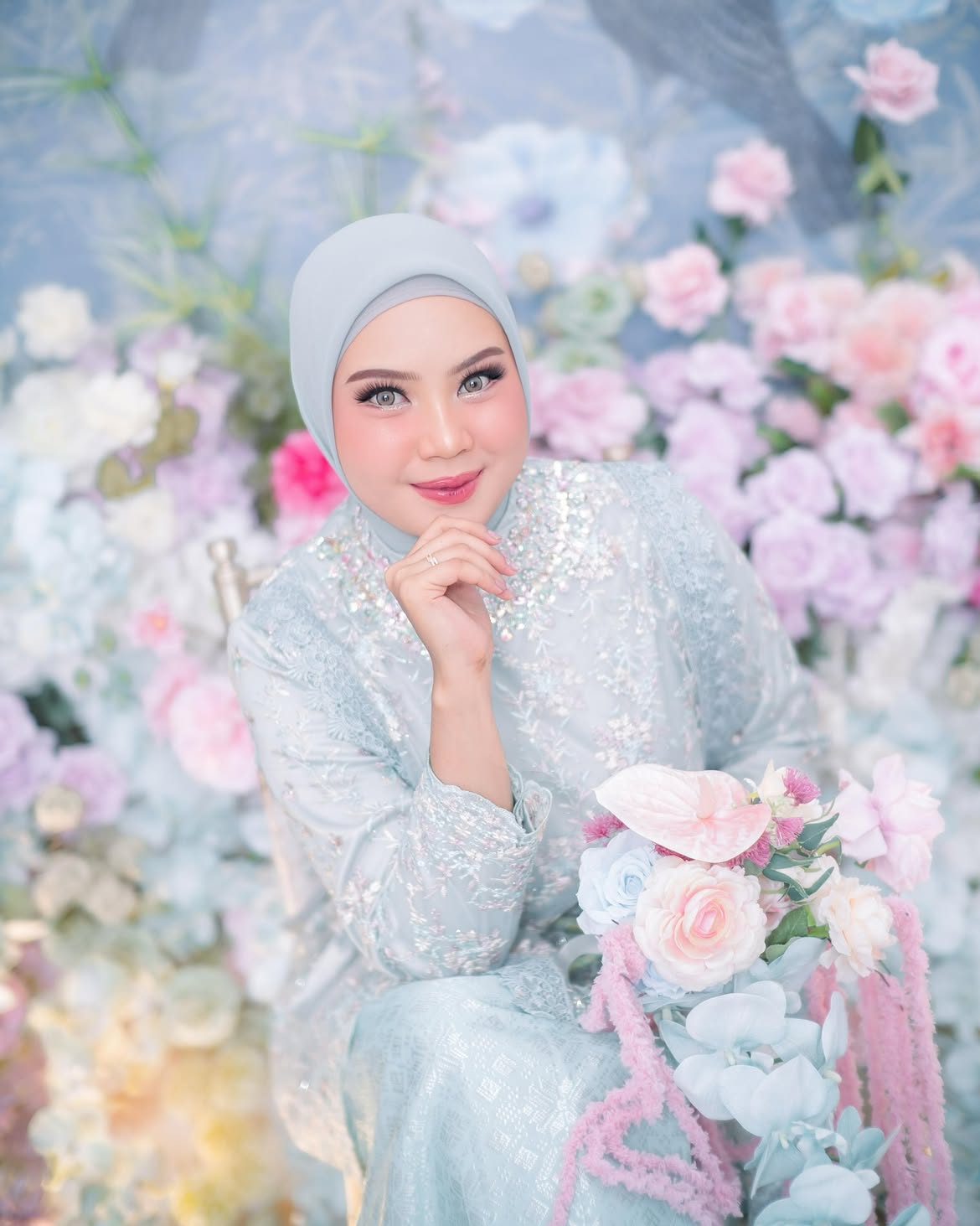 Rias engagement dengan gaun biru pastel berpayet, difoto di antara dekorasi bunga