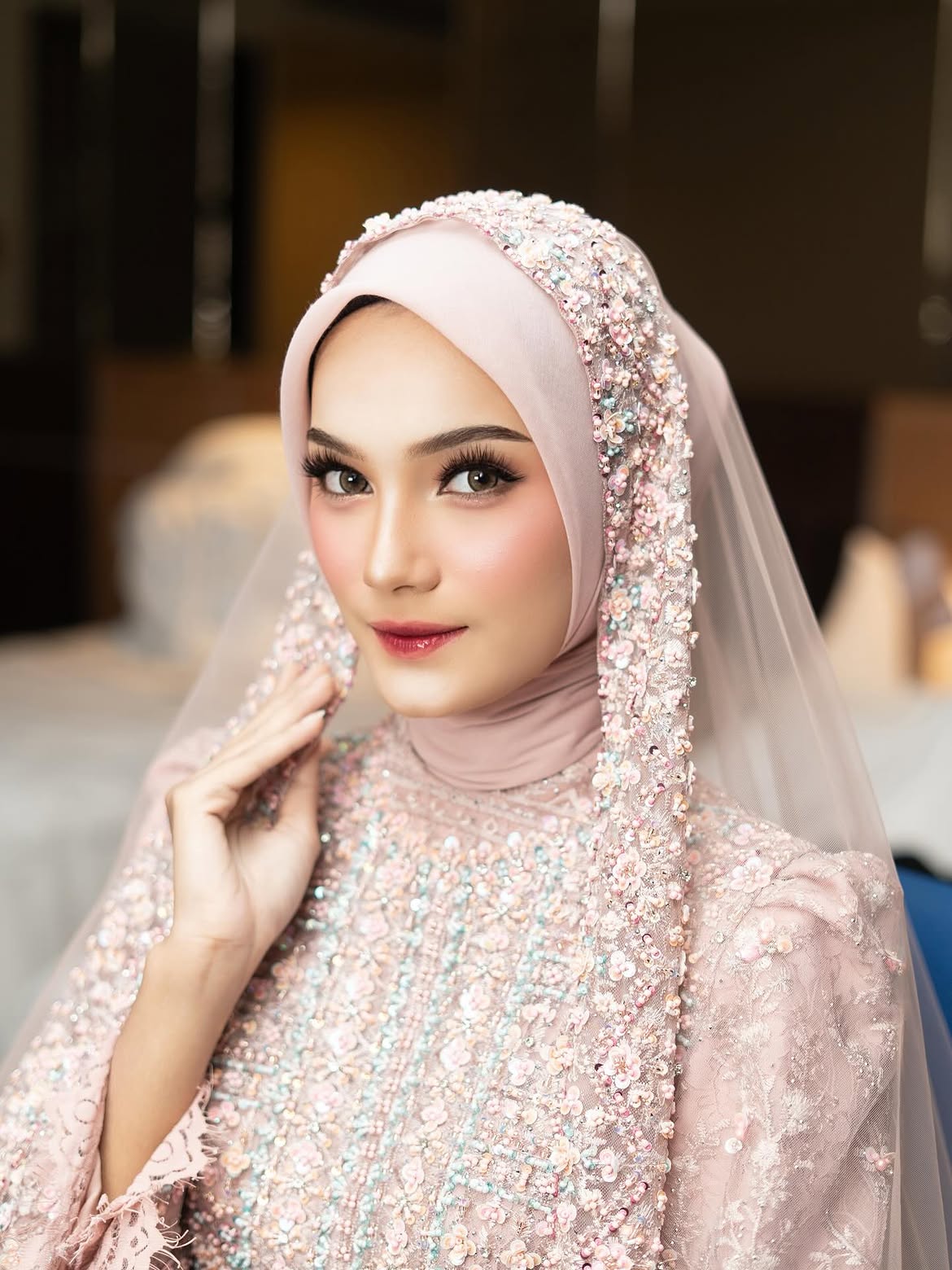 Rias dengan hijab merah muda berhias payet dan riasan mata soft glam